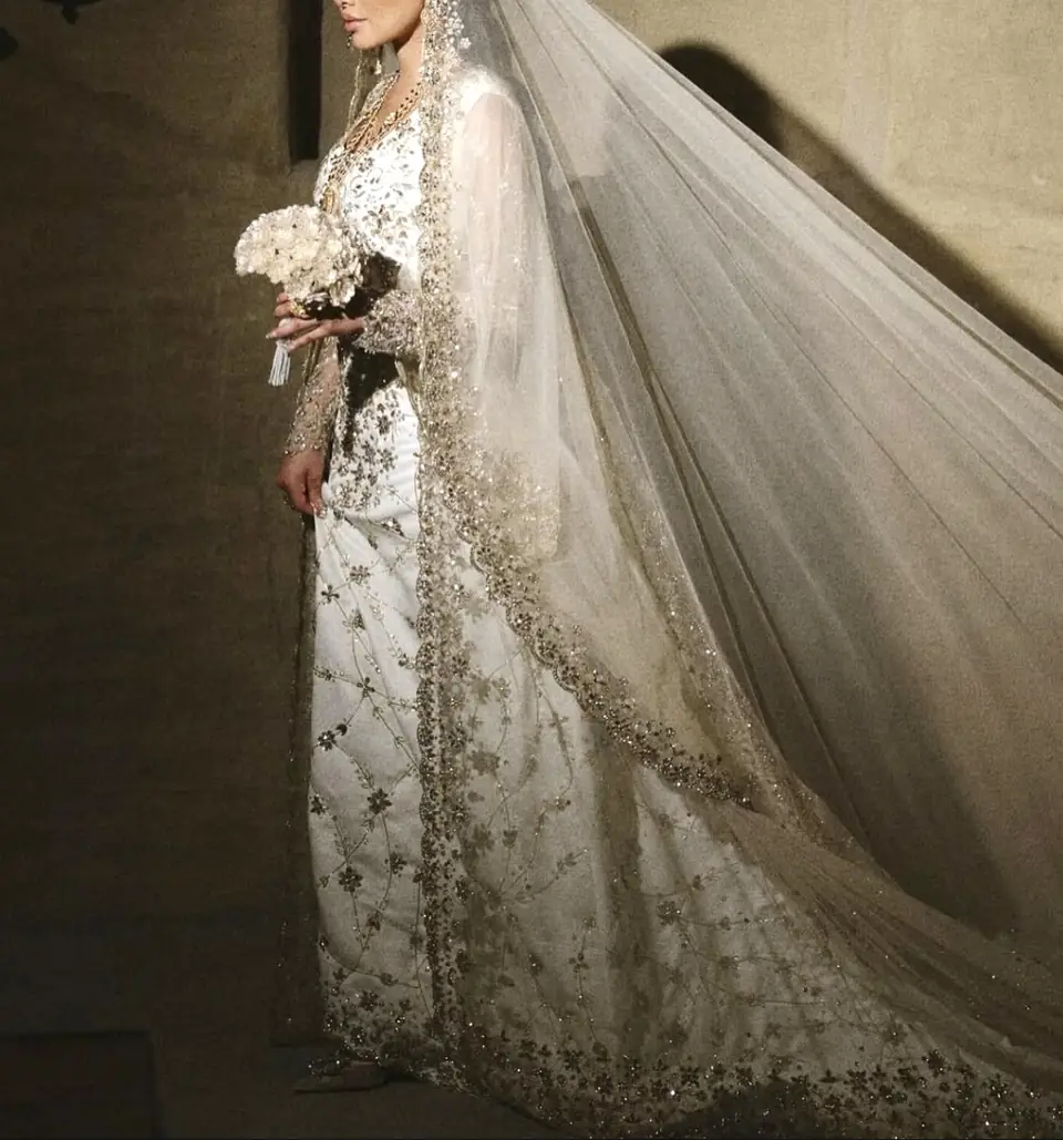 Side view of a gold-embroidered bridal gown with a long sweeping tulle veil