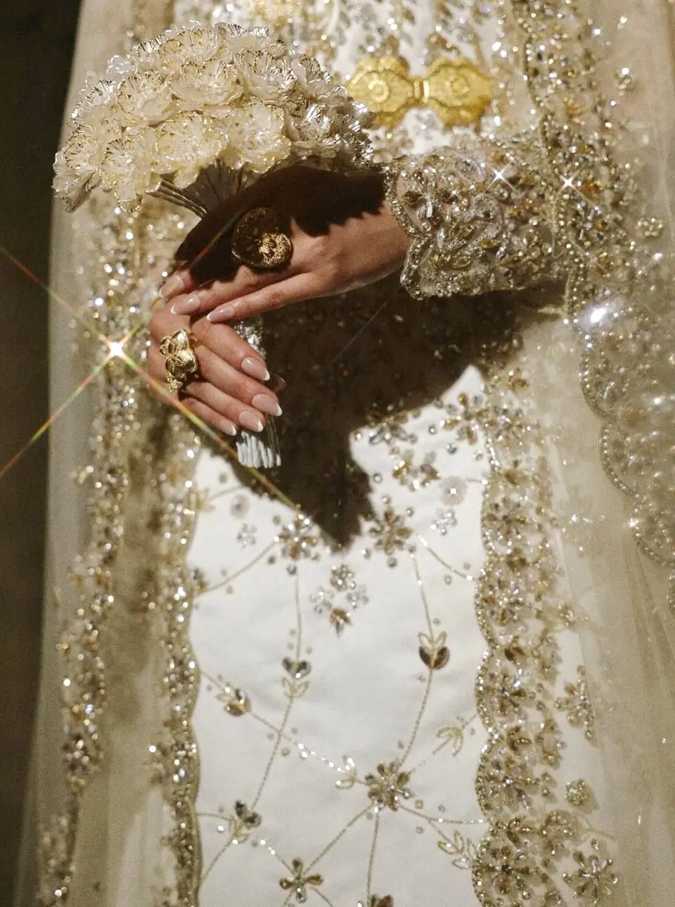 Close-up of crystal and gold bead embroidery on an ivory bridal gown with a gold belt
