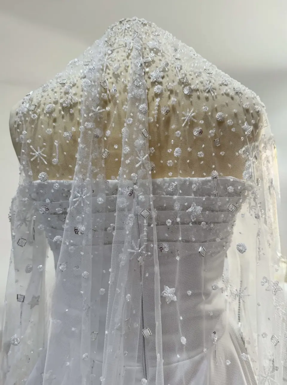 Back view of a tulle veil hand-beaded with stars, florets and crystals over a pleated satin bodice