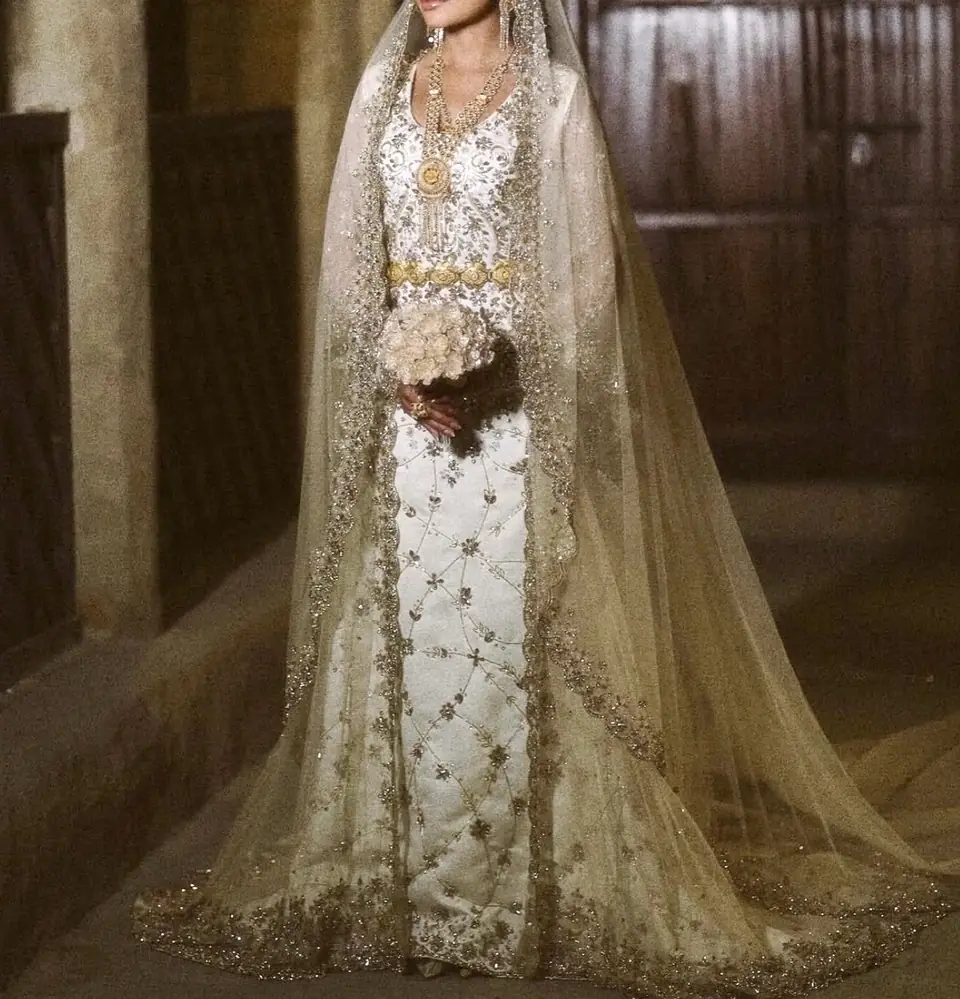 Ivory column bridal gown with gold trellis embroidery, a gold belt and an embroidered tulle veil