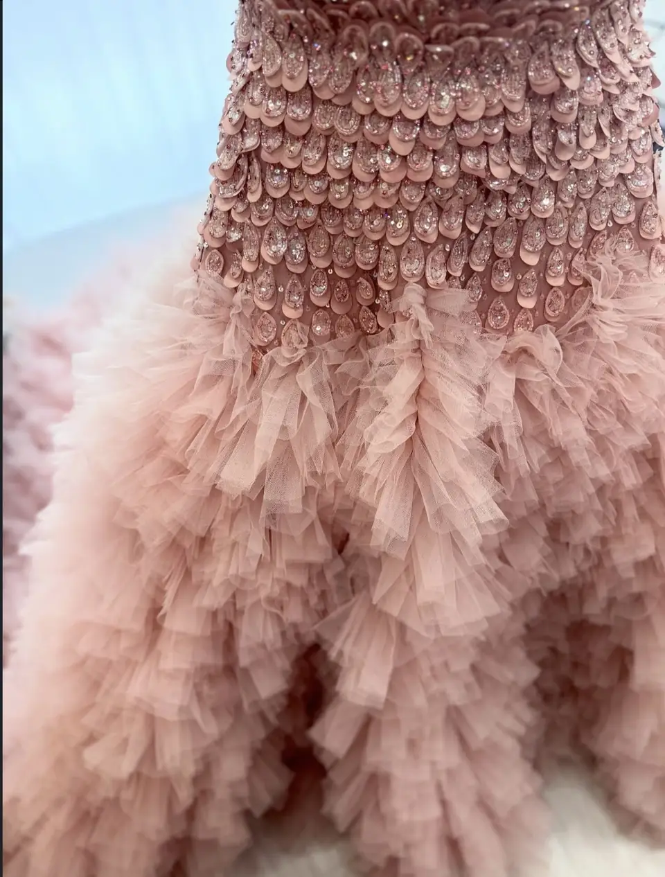 Layered ruffled blush tulle skirt beneath a crystal petal bodice