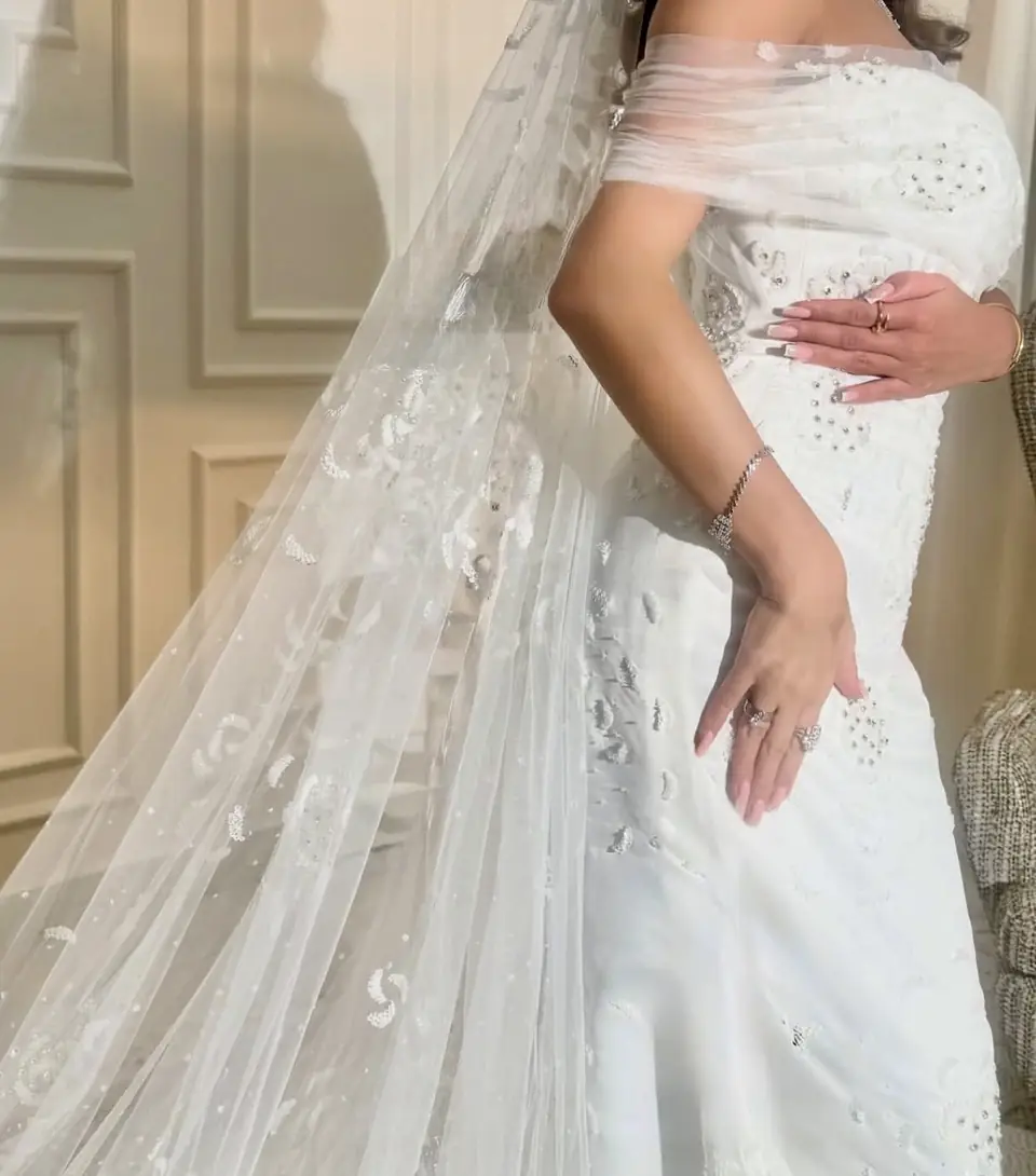 Off-shoulder draped tulle wedding dress with scattered hand beading and matching veil