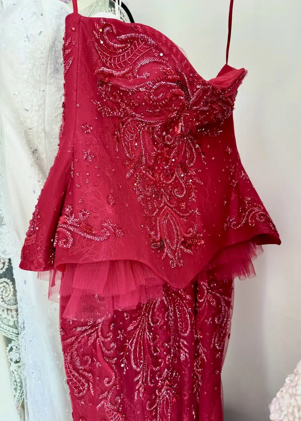 Red hand-beaded corset gown with a tulle peplum on a dress form
