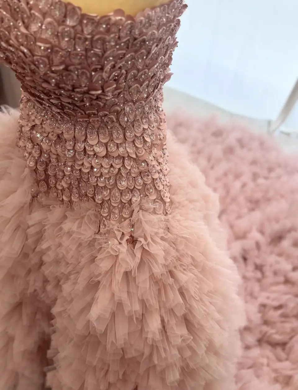 Detail of a hand-applied petal bodice with crystal centres above ruffled blush tulle