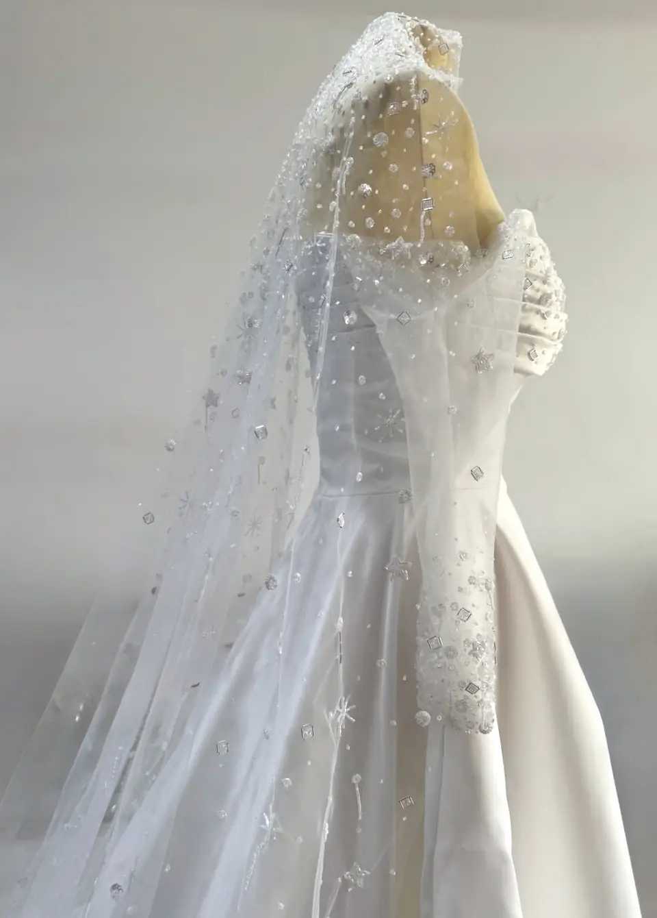 Satin bridal gown with a star and crystal hand-beaded tulle veil on a dress form